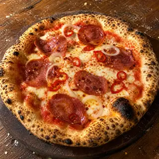 Diavola frisch aus dem Ofen, belegt mit Salami, Scharfe Peperoni, Zwiebelringe, Chiliflocken