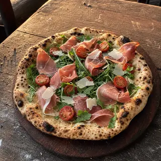 Parma e Rucola frisch aus dem Ofen, belegt mit Parmaschinken, Rucola, Kirschtomaten, Parmesanspäne
